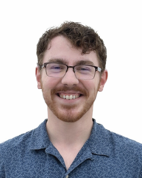 Smiling person with glasses and patterned shirt.