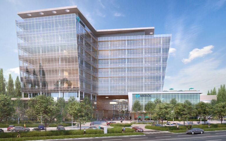 Modern glass building with trees and parked cars.