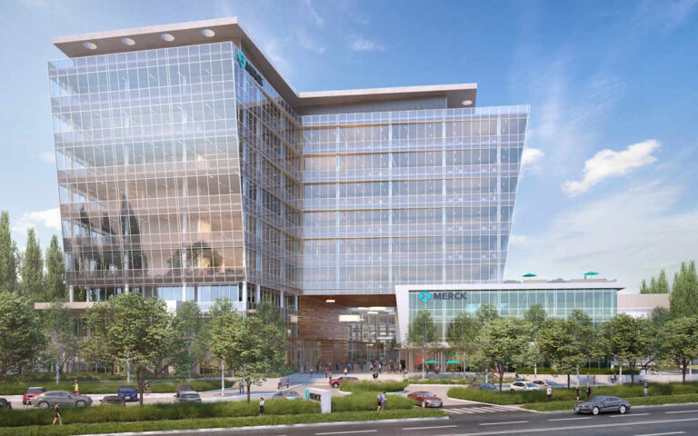 Modern glass building with trees and parked cars.