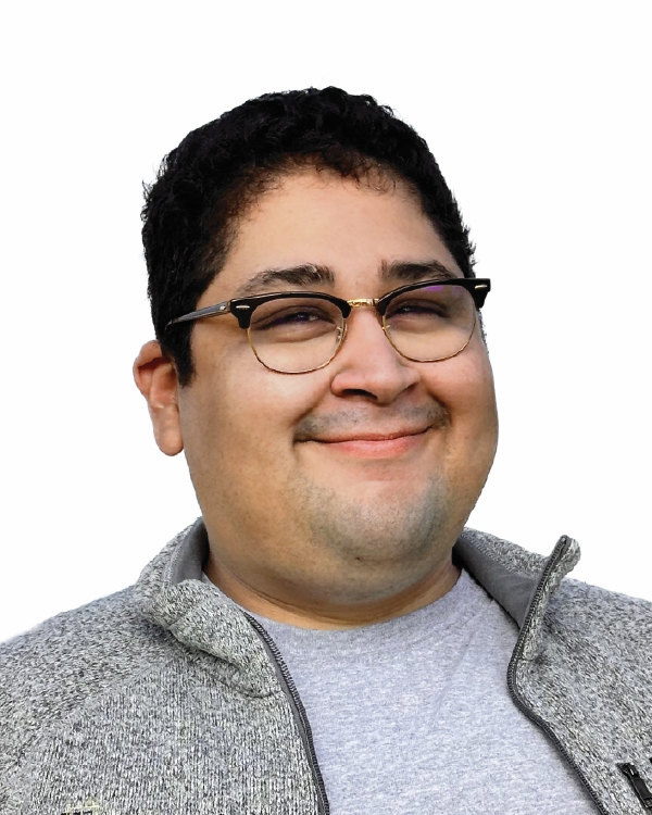 Smiling person with glasses and gray jacket.
